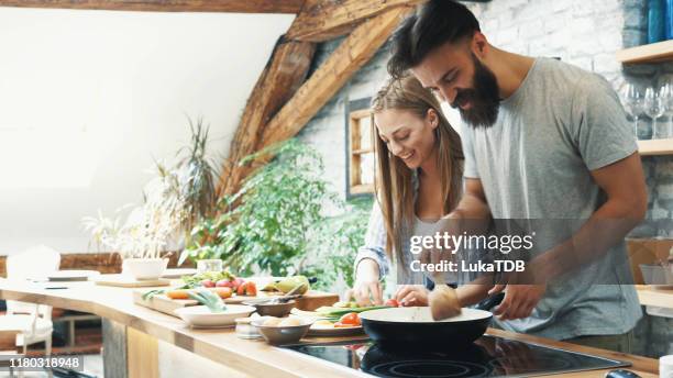 young couple making dinner together at home - young couple cooking stock pictures, royalty-free photos & images