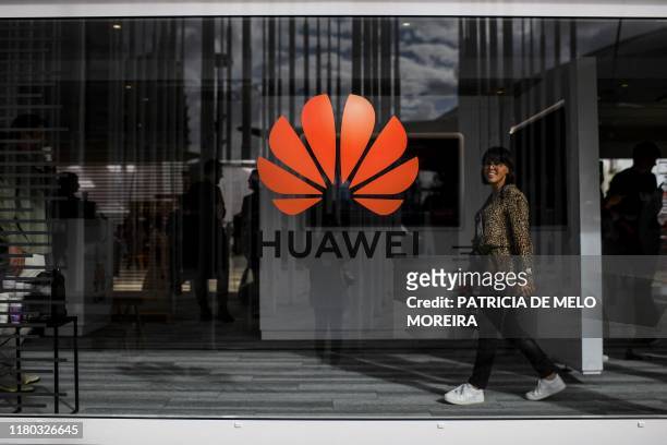 Woman walks past the logo of Chinese telecom giant Huawei during the Web Summit in Lisbon on November 6, 2019. - Europe's largest tech event Web...