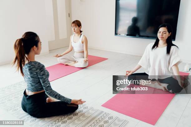 millennial-aged women learning and practicing yoga - yoga studio stock pictures, royalty-free photos & images