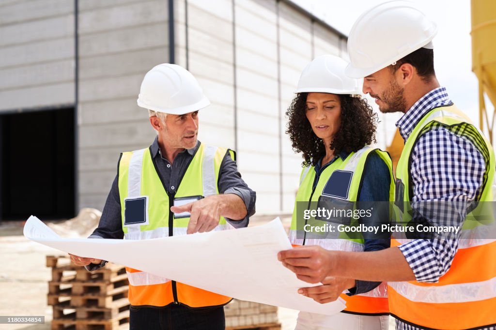 Three construction engineers going over building plans on a worksite