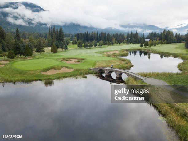 les golfeurs traversent le pont vers le putting green - cross golf photos et images de collection