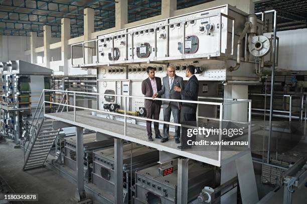 indian ceo and associates talking in mumbai textile factory - manufacturing machinery stock pictures, royalty-free photos & images
