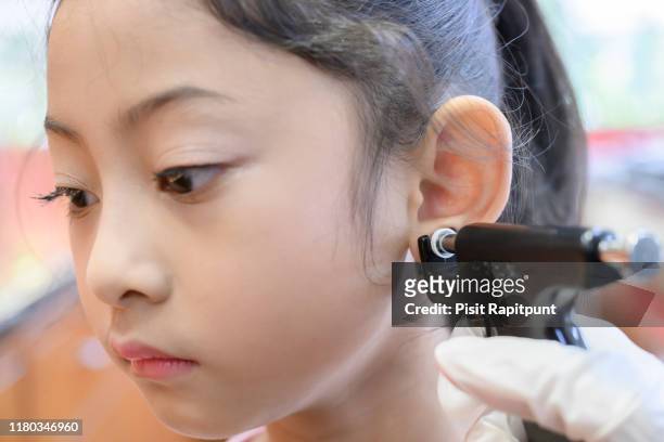 adorable little asian girl having ear piercing process. - boucle d'oreille photos et images de collection