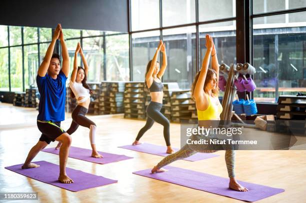 group of young sporty people practicing yoga lesson. - yoga studio stock pictures, royalty-free photos & images