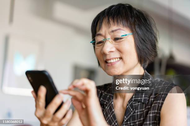 mujer asiática senior usando un teléfono inteligente - old phone fotografías e imágenes de stock