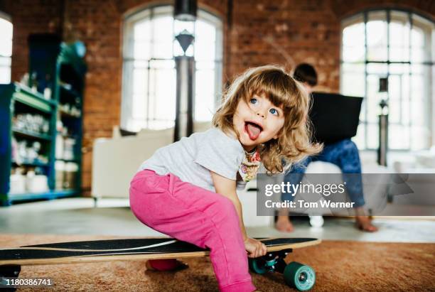 toddler playing on skateboard indoors - pink pants stockfoto's en -beelden