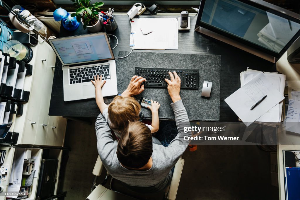 Aerial View Of Mother Working In Office At Home With Daughter