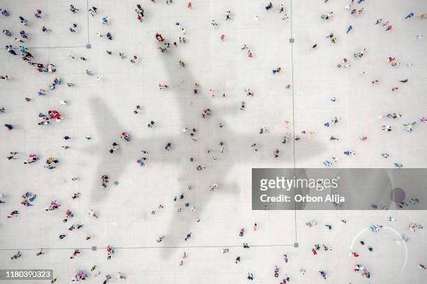 aerial view of crowd with airplane shadow - crowded plane stock pictures, royalty-free photos & images