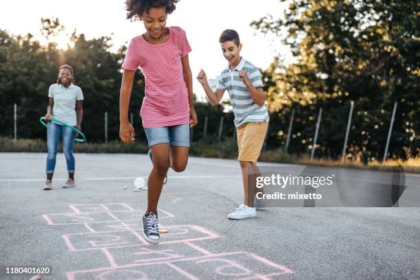doen wat kinderen het beste doen, springen voor vreugde - hinkelspel stockfoto's en -beelden