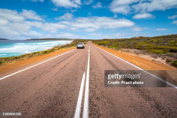 view from empty country road sightseeing scenic landscape view of great ocean road in victoria, australia. bright sunny summer day with warm light and blue sky with cloud and surfing wave. famous drive route in australia. - road australia stockfoto's en -beelden