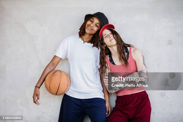 Two beautiful young women with basketball in hand leaning on each other