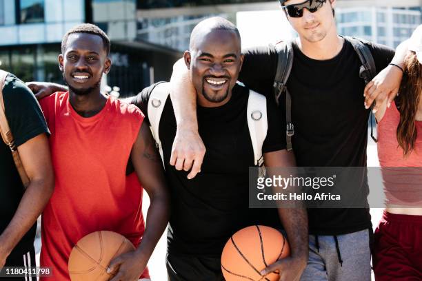 Group of friends holding basketballs standing with arms around each other