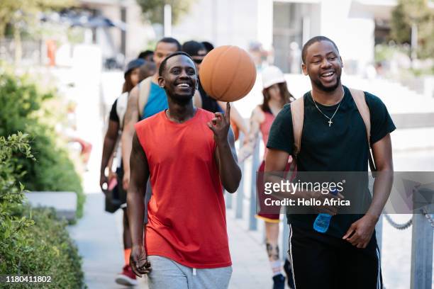 Happy group of friends walking and talking and spinning a basketball