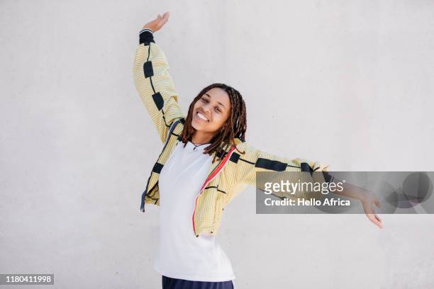 happy young beautiful woman wearing yellow and raising arms in the air - woman effortless stock pictures, royalty-free photos & images