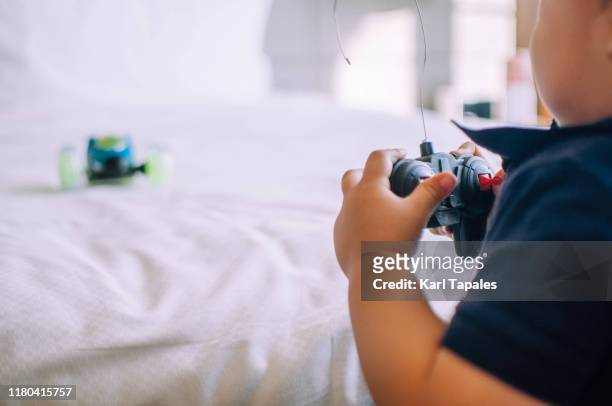a male toddler is playing with his remote controlled car indoors - remote controlled car fotografías e imágenes de stock