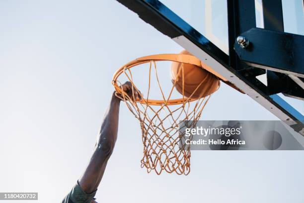 A basketball player's hand grips the edge of the hoop he scores