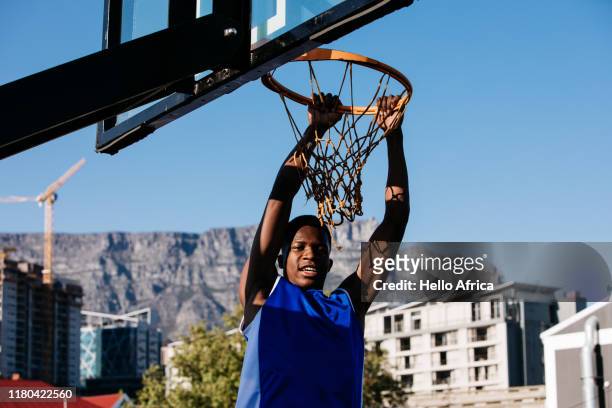 Basketball player happily hanging on hoop after scoring
