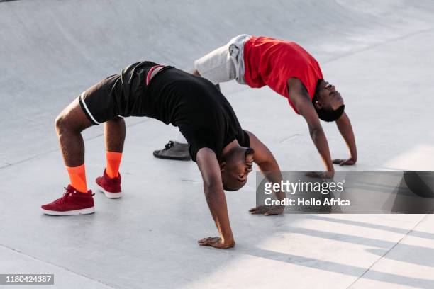 two flexible sportsman illustrating yoga bridge to wheel pose whilst warming up - coaching formacion stock-fotos und bilder