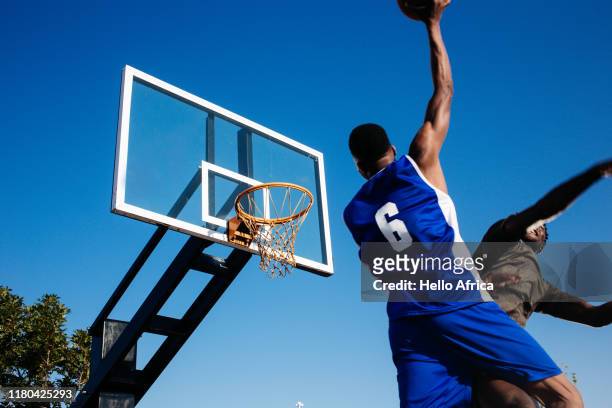 Low angle view of strong basketball player with ball in one hand aiming to score