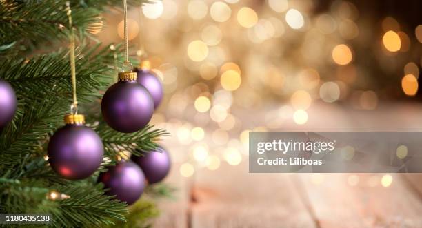 arbre de noel avec des boules pourpres et le fond de lumières d'or - mauve des bois photos et images de collection