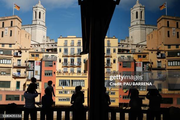 Silhouettes of people looking at the view over the Onyar river in Girona, on November 2, 2019. - Across Girona, countless yellow, red and blue...