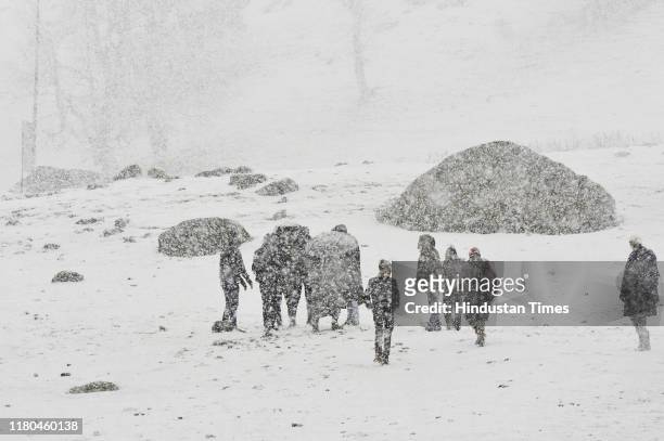 People walk during first snowfall on November 6, 2019 in Sonamarg, some 90 kilometers from Srinagar, India. The upper reaches of Kashmir received...