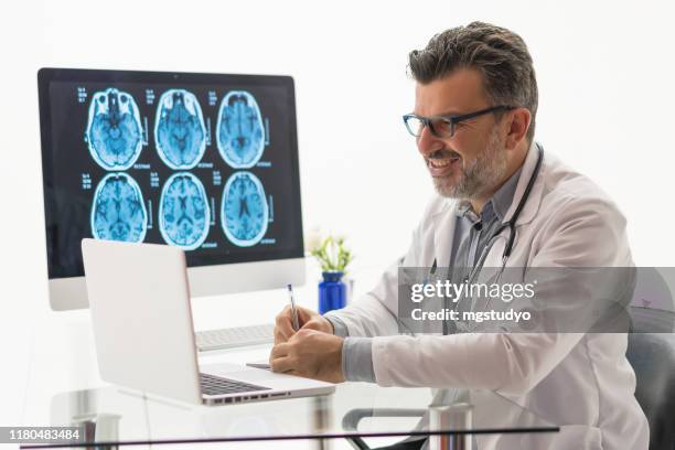 doctor working on desk with laptop - neurologist stock pictures, royalty-free photos & images