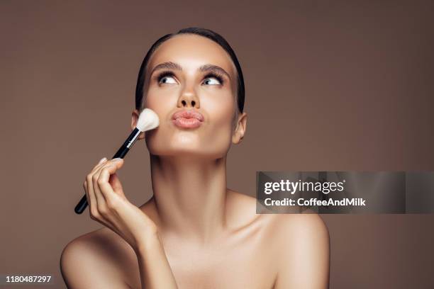 beautiful young woman applying foundation powder - pincel de blush imagens e fotografias de stock