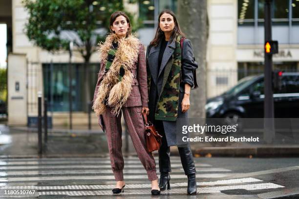 Sylvia Haghjoo wears a brown and burgundy Prince of Wales check jacket, assorted baggy pants, a black and green knit scarf decorated with feathers, a...
