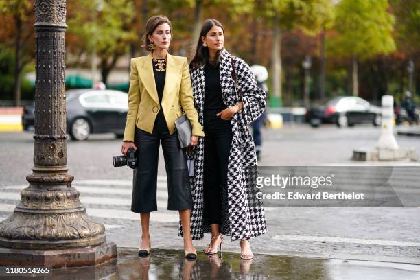 Sylvia Haghjoo wears Chanel earrings, a Chanel necklace, a yellow jacket, a black top, black leather wide-legs crop pants, a grey clutch, Chanel...