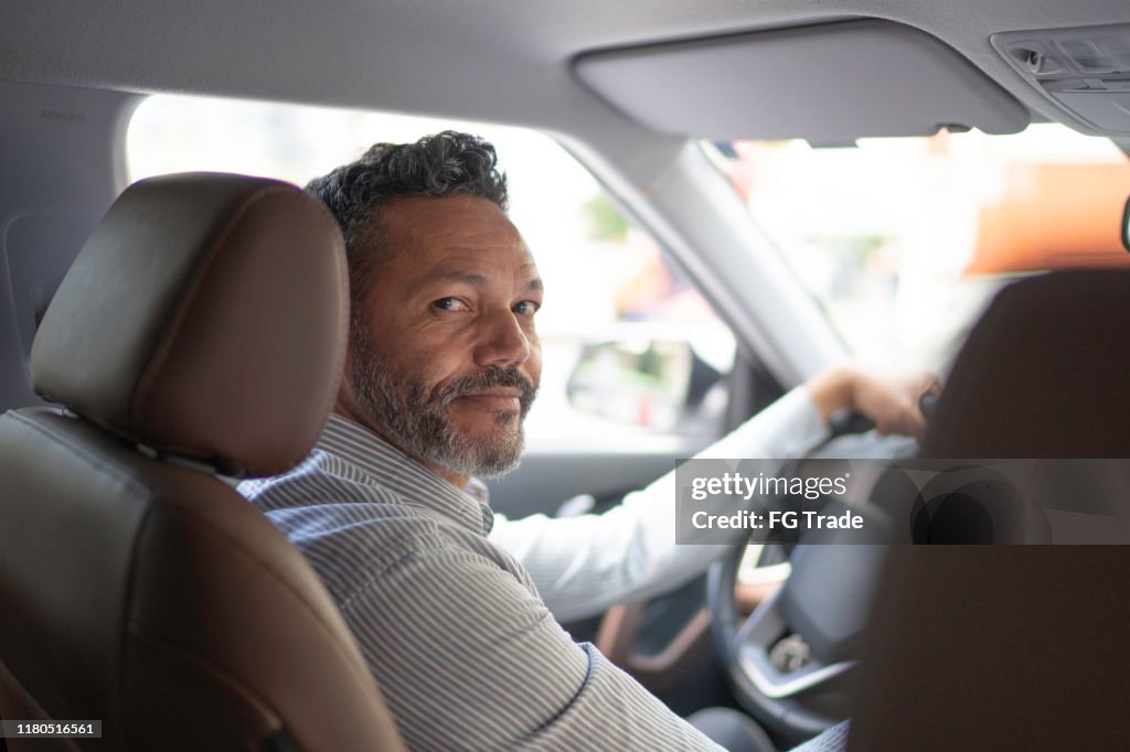 Portrait of businessman looking at camera inside the car