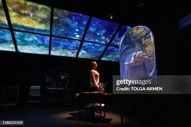 Gallery worker poses with a projection of the painting, 'The Virgin of the Rocks' by Leonardo da Vinci in a reimagined studio room during a photocall...