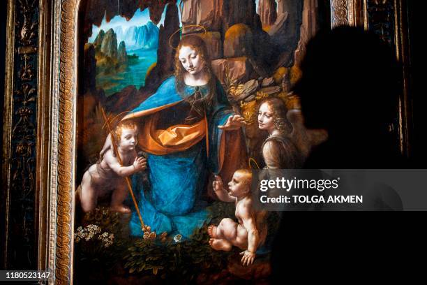 Gallery worker poses with the painting 'The Virgin of the Rocks' by Leonardo da Vinci during a photocall for the upcoming 'Leonardo: Experience a...