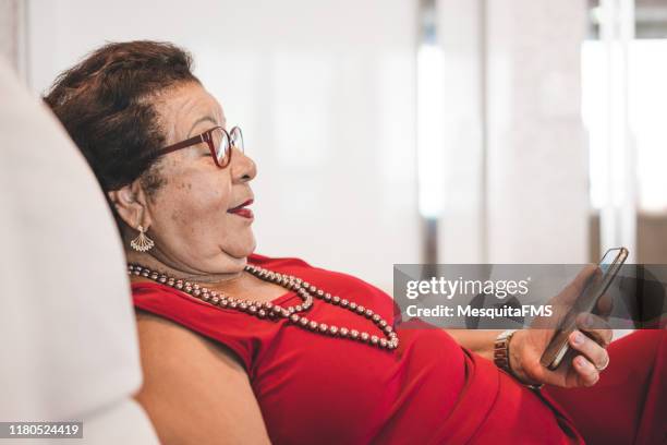 grandmother using smart phone on the sofa - grandparent phone stock pictures, royalty-free photos & images