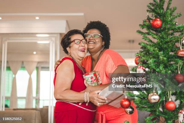 mother and daughter celebrating christmas at home - giving tree stock pictures, royalty-free photos & images