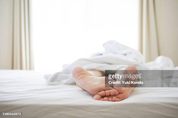 feet lying on the bed. - feet in bed stock-fotos und bilder