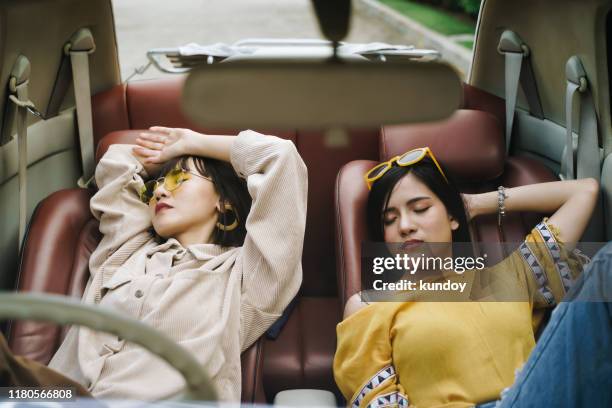 portrait of two friends sleeping together in car. freedom and relax in road trip concept. - sleeping in car stockfoto's en -beelden