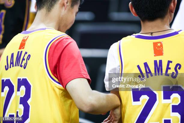 Fans of LeBron James of the Los Angeles Lakers use a Chinese National flag logo to cover the NBA logo while attending the match during a preseason...