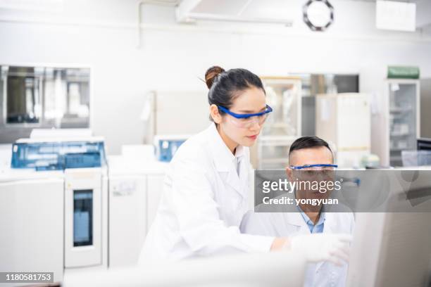 asian scientists using a computer in a medical laboratory - chinese scientist stock pictures, royalty-free photos & images