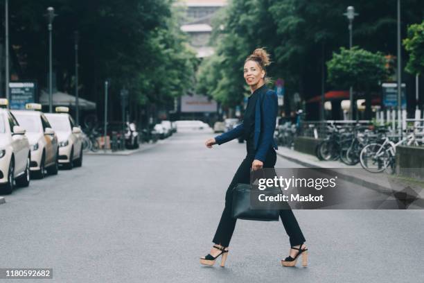 side view of businesswoman crossing street in city - woman walking side view stock pictures, royalty-free photos & images