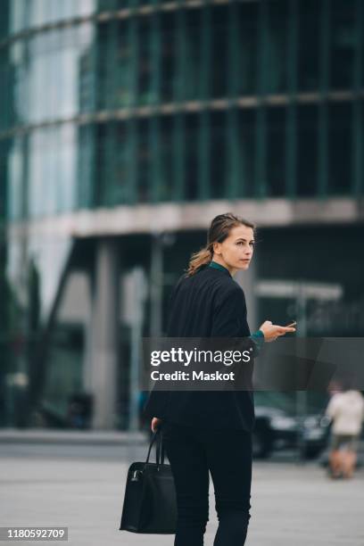 businesswoman looking over shoulder while walking on street in city - business woman looking over shoulder stock pictures, royalty-free photos & images