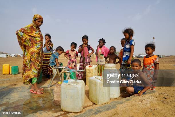Women and children gather water at an IDP settlement in northern Burkina Faso.