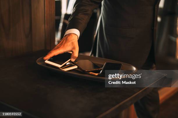 midsection of male lawyer keeping smart phone on tray at office - phone tapping stockfoto's en -beelden