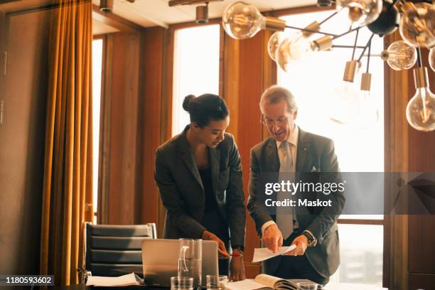 mature legal professional explaining female colleague in meeting at board room - professione giuridica foto e immagini stock