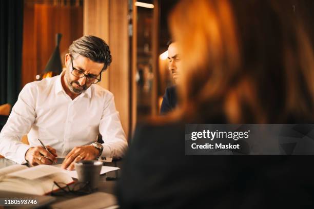mature lawyer signing documents during meeting at law office - 50s woman writing at table imagens e fotografias de stock