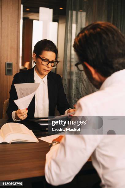 female financial advisor reviewing documents while sitting with customer in meeting at office - legal problems stock pictures, royalty-free photos & images