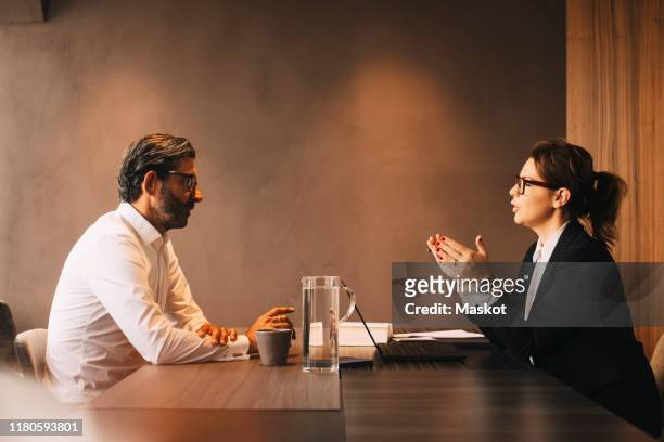 side view of female lawyer explaining mature client in meeting at office - judiciary hearing stock pictures, royalty-free photos & images