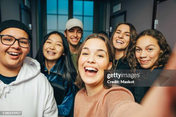 cheerful teenage classmates taking selfie in corridor - alleen tieners stockfoto's en -beelden