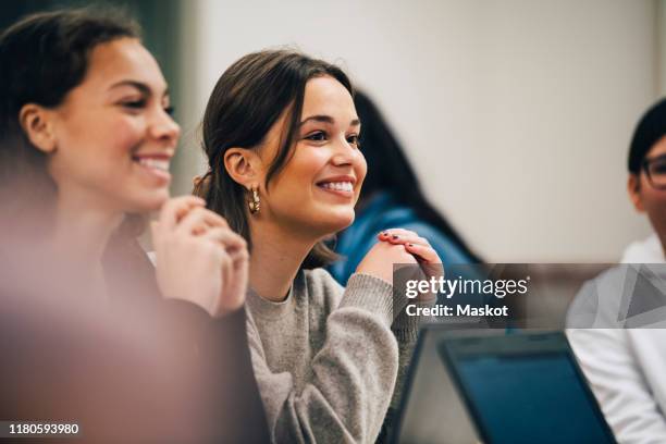 smiling female students looking away while sitting in classroom - freshman class 2018 stock pictures, royalty-free photos & images