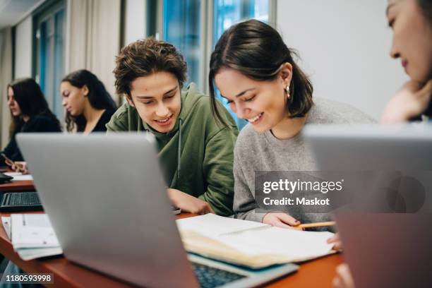 smiling teenage students studying at desk in school - teenage boys stock photos et images de collection